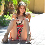 Cute teen Ellie hikes up her dress to masturbate on a public veranda