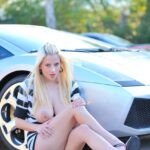 Kinky blonde MILF Haley shows her huge boobs and poses in front of a car
