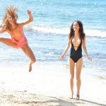 2 lesbians frolic in swimsuits at the beach before strolling in the nude